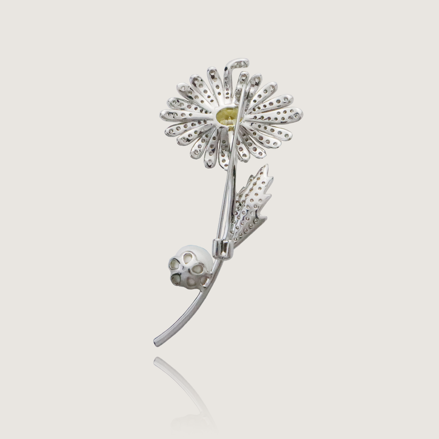 Elegant floral pin with sparkling diamonds, vibrant yellow centerpiece, and pearl detail.