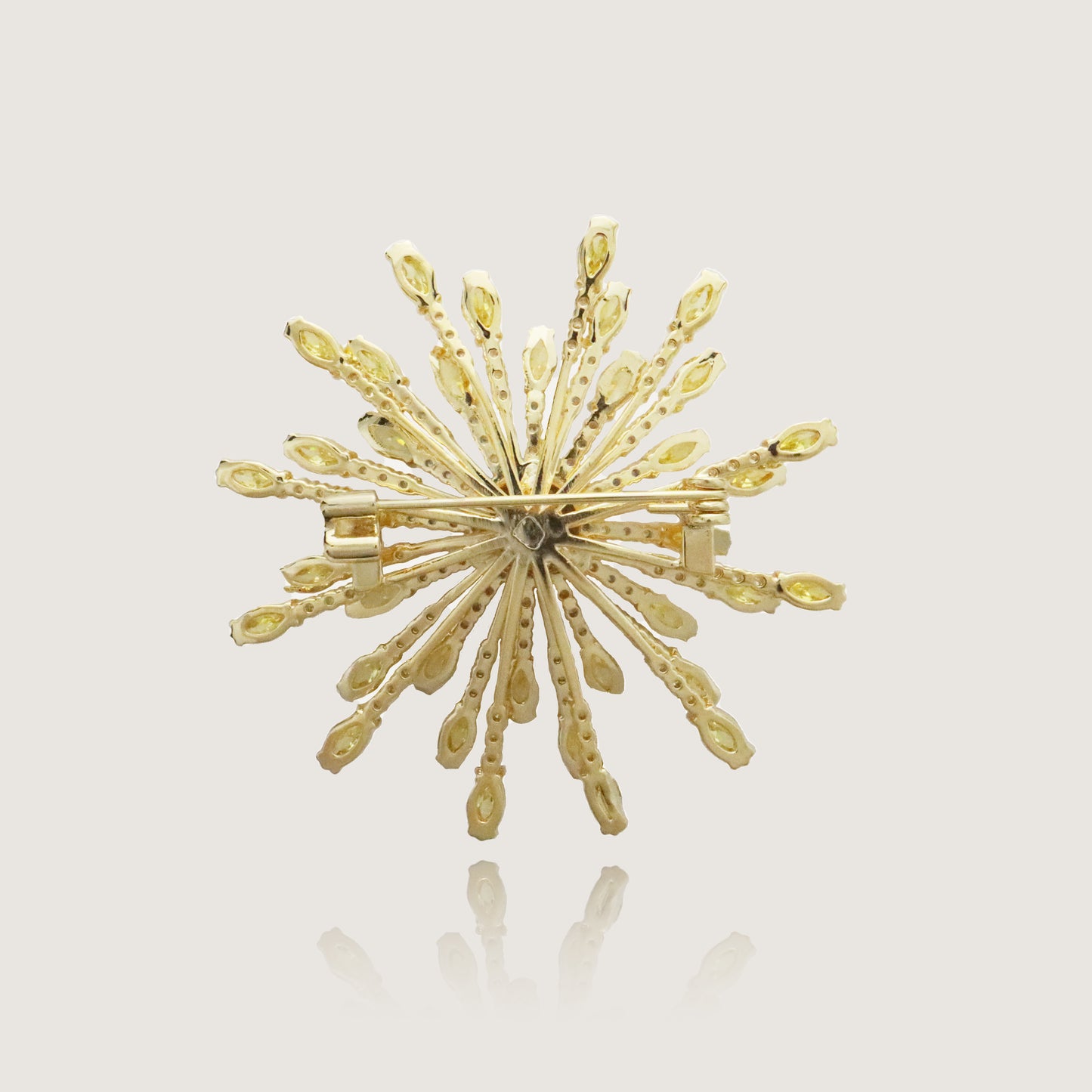 Sunburst gold brooch featuring a sparkling center and yellow gemstone spokes