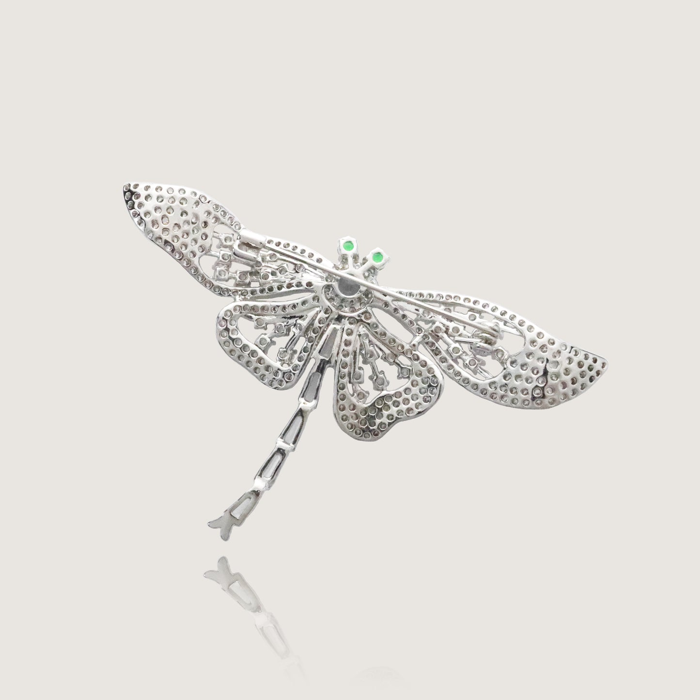 Elegant filigree dragonfly brooch with a crystalline body and striking green eyes