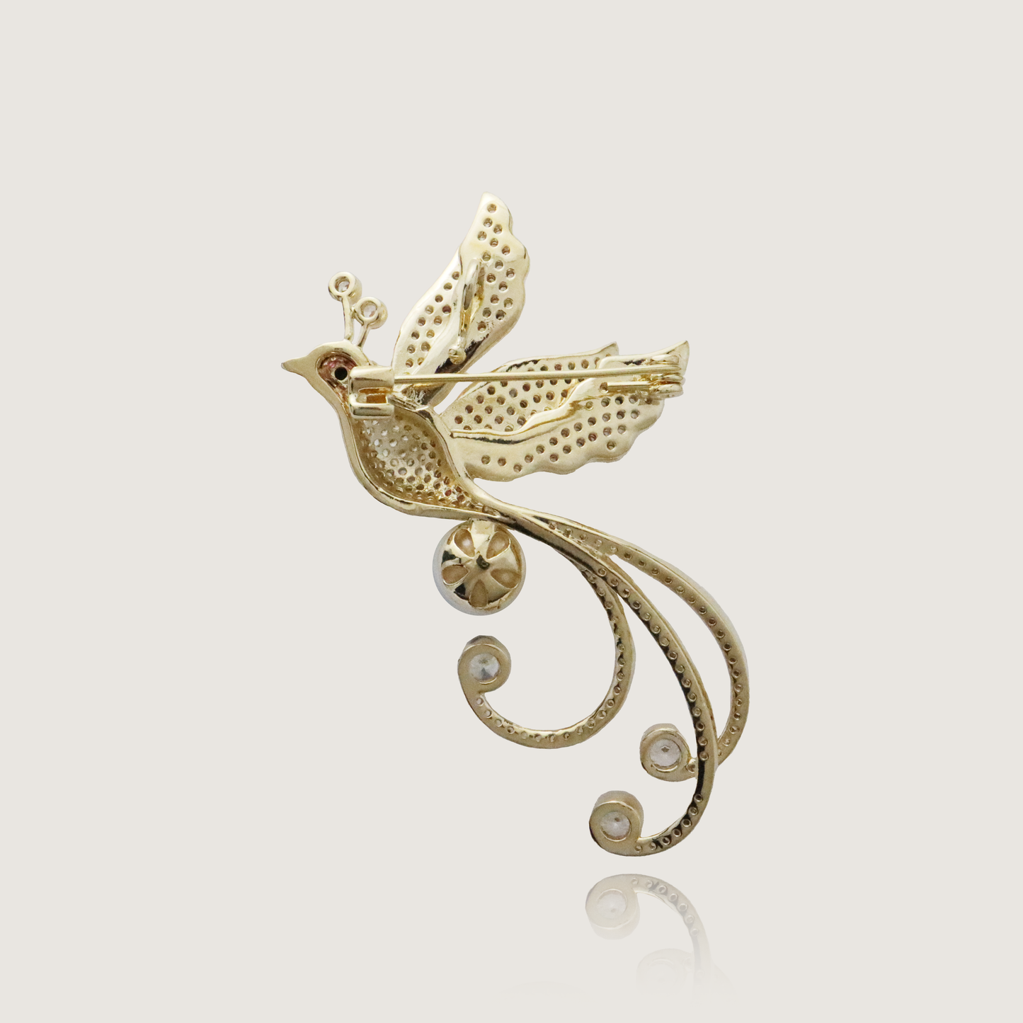 Elegant golden bird brooch with shimmering wings, pearl detail, and gemstone accents