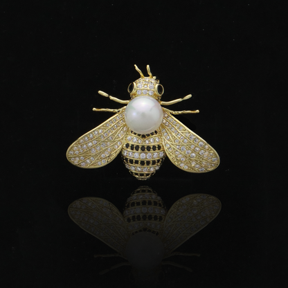 Elegant insect-inspired pin with sparkling wings and a lustrous central pearl.