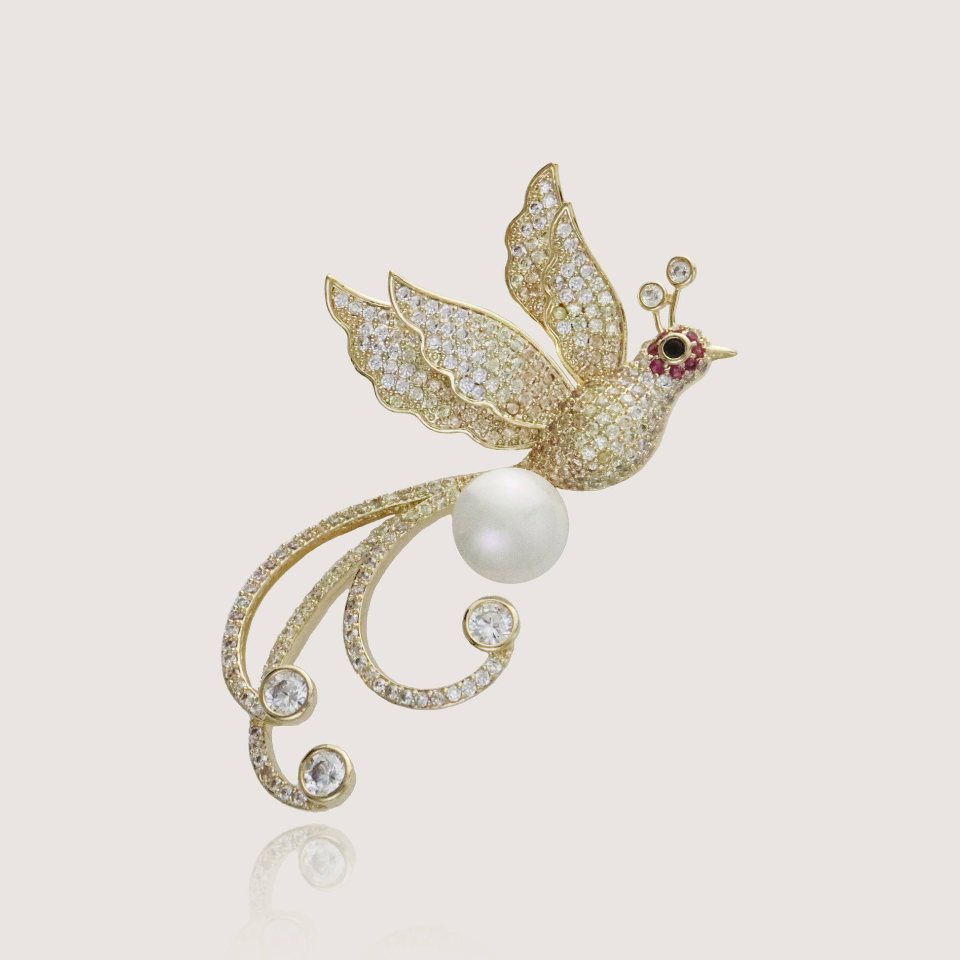 Graceful bird brooch with golden feathers and a pearl, encrusted with crystals