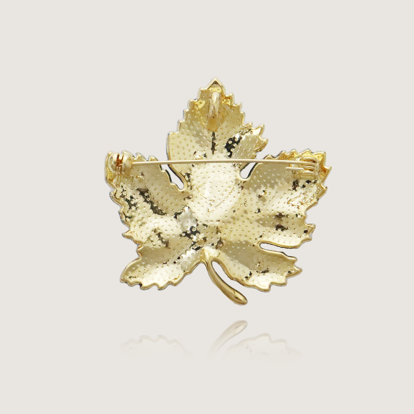 Luxurious jewel-toned maple leaf brooch with sapphire accents and golden detail