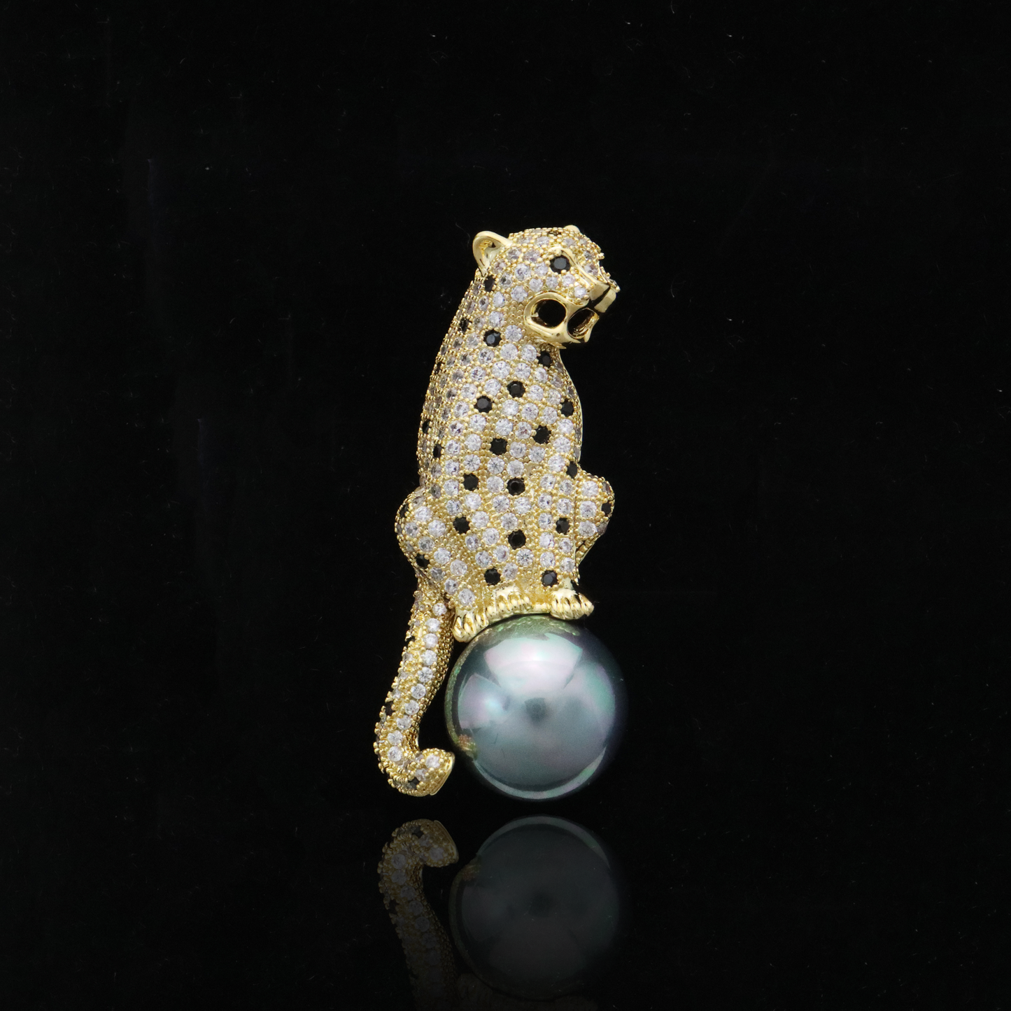 Gold-tone leopard brooch studded with sparkling diamonds and featuring a hanging grey pearl, embodying vintage luxury.