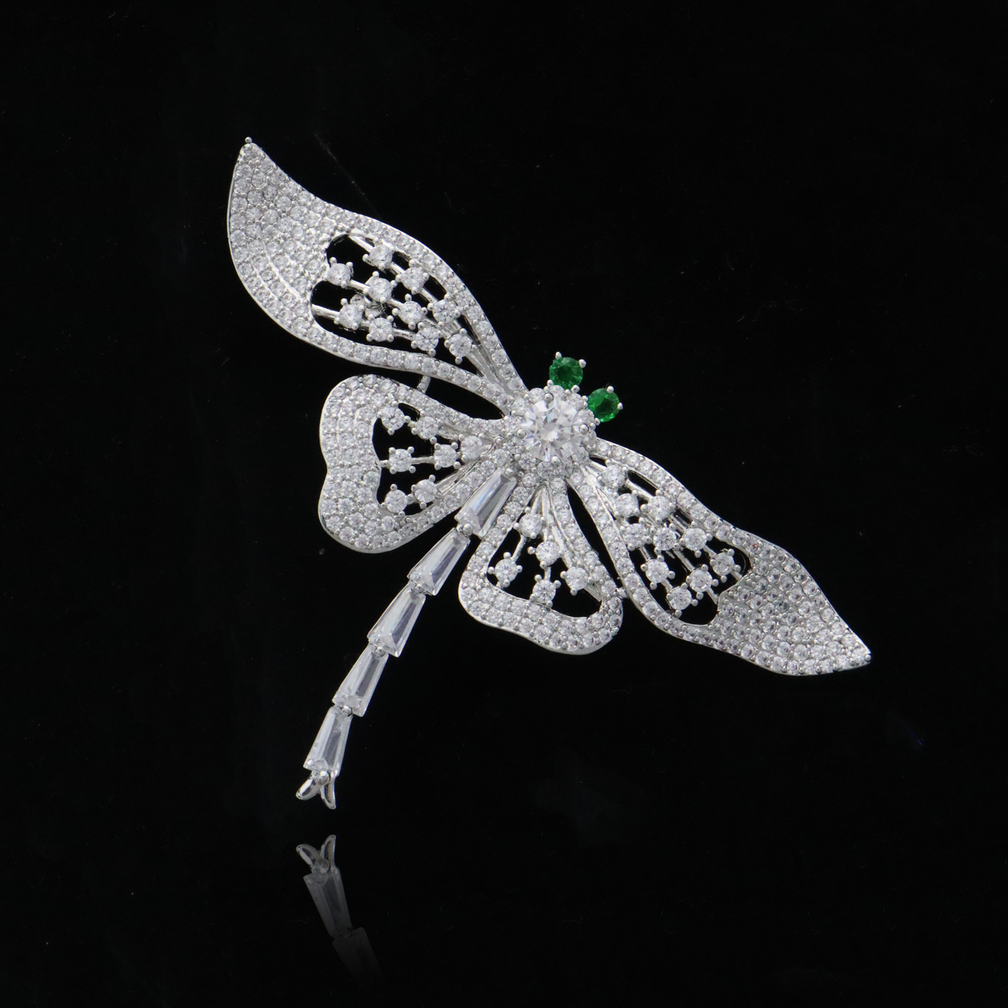 ntricate silver dragonfly pin featuring a dazzling pavé design with emerald-like accents